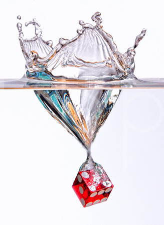 In this photograph a large red casino die hits the surface of clear water at high speed creating an underwater vortex in this commercial product photograph by Brian Buckner Photography, Shreveport.