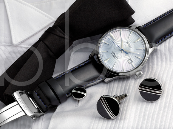 A SEIKO "Cocktail Time" Wristwatch is shown lying on a tuxedo shirt with cuff links and bow tie in this commercial product advertising photograph by Brian Buckner Photography, shreveport.