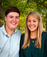 A Young Man And Woman, Both High School Seniors, Are Happy And Smiling As They Pose By Some Dappled Greenery in A Park while having their senior portrait made by Brian Buckner Photography, Shreveport.