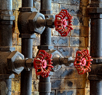 Red valve wheels are artisticly shown on an old wall with chipped paint in this commercial architectural photograph by Brian Buckner Photography, Shreveport, Louisiana.