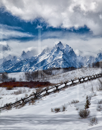 Wispy White Clouds Of Winter, Set Against A Blue Sky, Accent The Snow Covered Peak Of The Grand Teton in this commercial landscape photograph by Brian Buckner Photography, Shreveport, Louisiana.