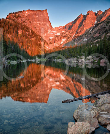Still and peaceful, Dream Lake in Rocky Mountain National Park reflects an image of the majestic Hallett Peak while it glows red with the light of the rising sun.