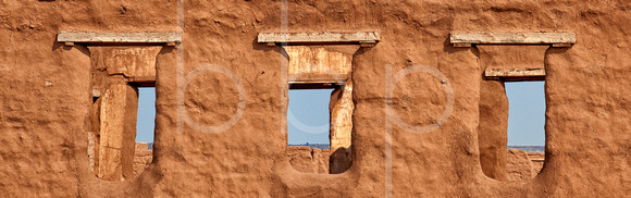At Fort Union National Monument on the Santa Fe Trail, early morning sun casts a warm glow on the old adobe window openings that frame the blue sky.