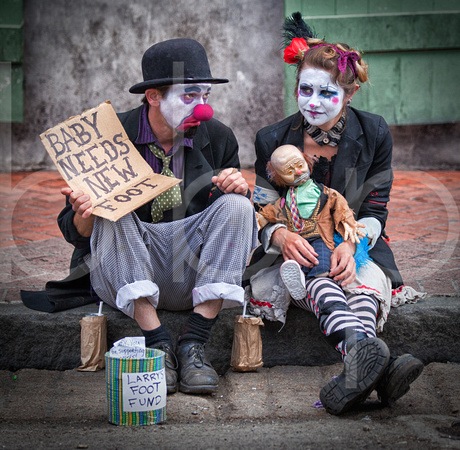 A Man And Wife Pair Of Bourbon Street, New Orleans Street Clowns, Using A Doll As Their Baby, Are Shown Begging For Money in this commercial environmental portrait by Brian Buckner Photography.