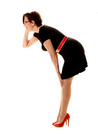 A Woman Is Posing On A Pure White Background With Red Spike High Heel Shoes, A Red Belt, Red Glasses And A Little Black Dress  In This Commercial Advertising Photograph By Brian Buckner Photography.