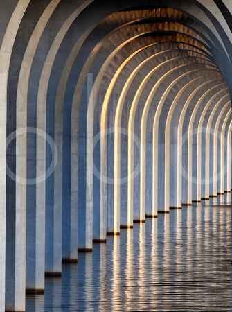 Pilings of a concrete bridge on Cross Lake in Shreveport, Louisiana  are shown repeating themselves across the lake in this commercial architectural photograph by brian buckner photography, shreveport